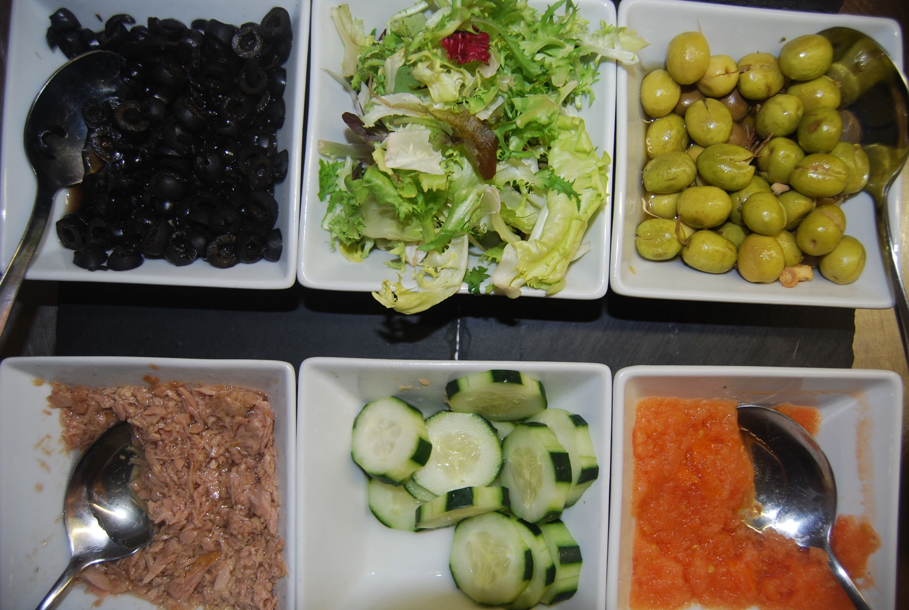 A table with four square dishes containing different food items.