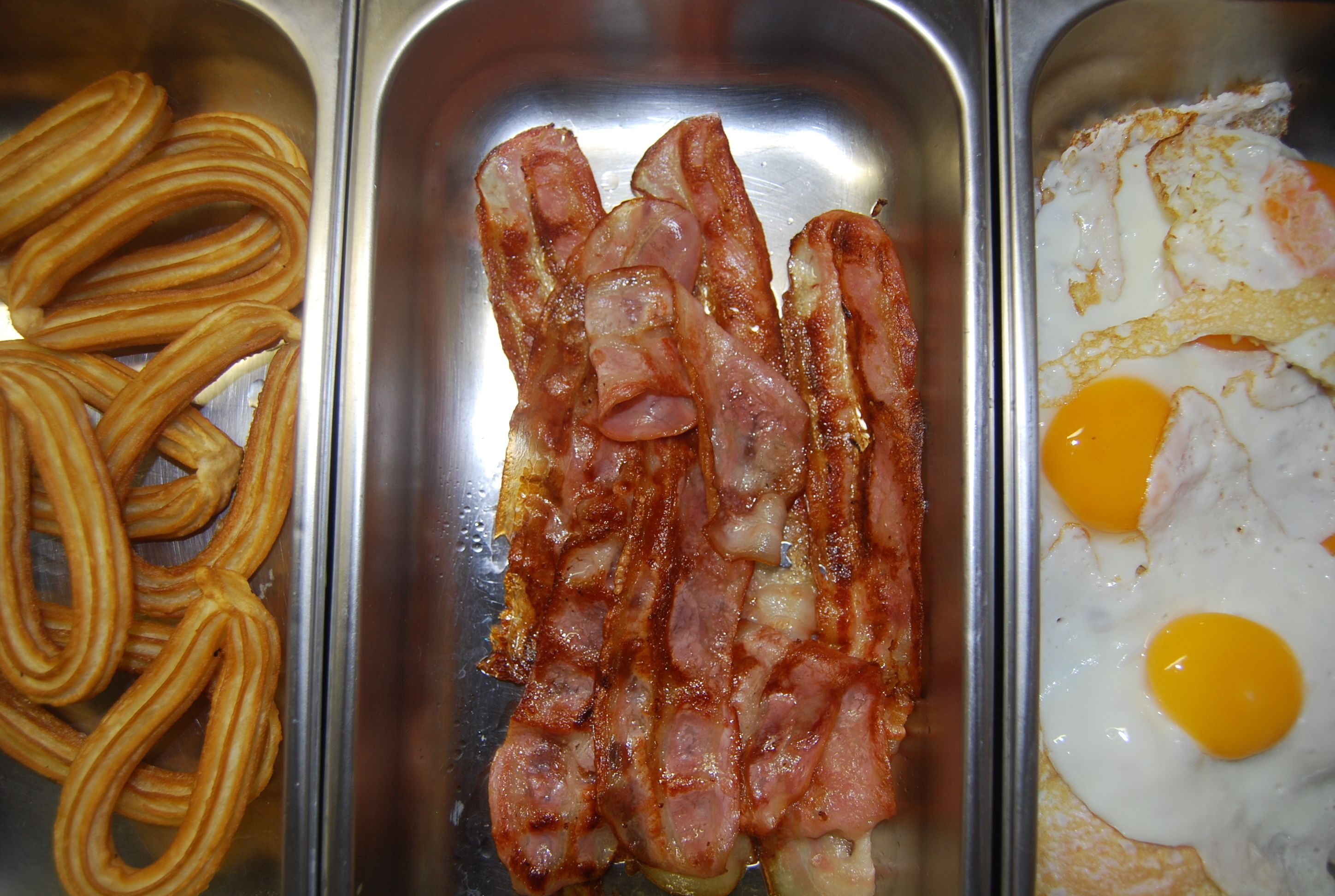 Ein Frühstücksbrett mit Churros, Speck und Spiegeleiern.