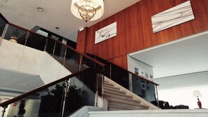 A grand staircase with a chandelier, wooden paneling, and modern art on the walls. - Hotel Mir Octavio (Algeciras)