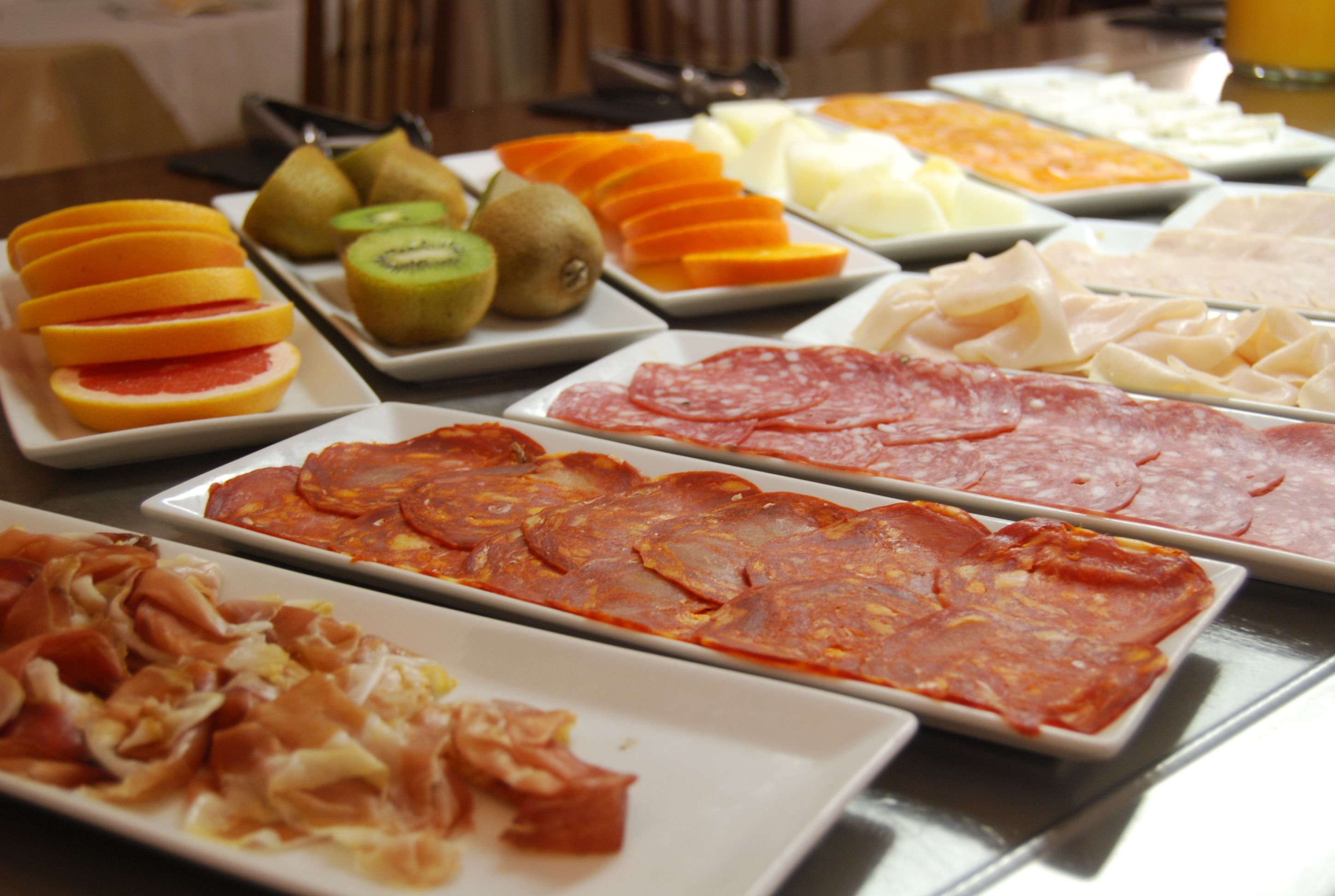 A buffet with various food items including sliced fruits, cheeses, and meats.