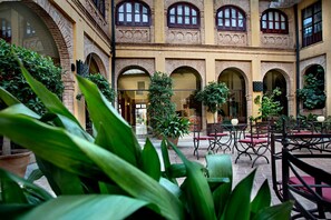 Un patio al aire libre con arcos de ladrillo, plantas en macetas y mobiliario exterior.