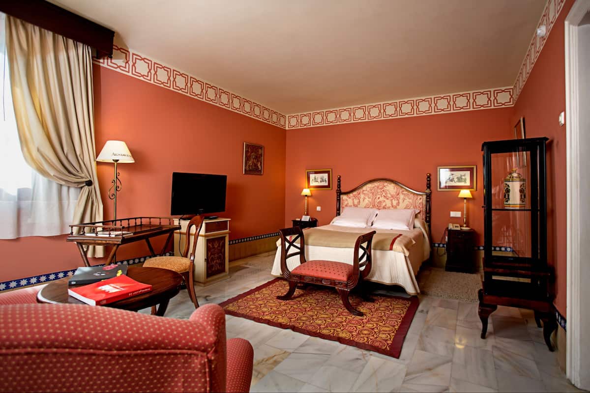 Una habitación de hotel con una cama, un escritorio, una silla, un televisor y una lámpara.
