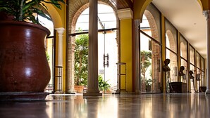 Un hall d’entrée spacieux, doté de hauts plafonds, de grandes colonnes et d’un sol carrelé.