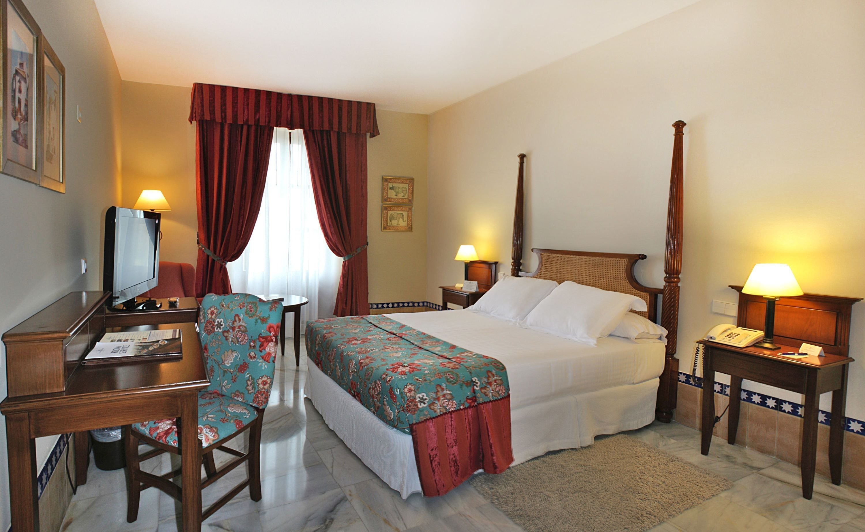 A hotel room with a bed, desk, chair, and a television.