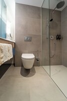 Un baño moderno con ducha envuelta en vidrio, un inodoro y un perchero para toallas.