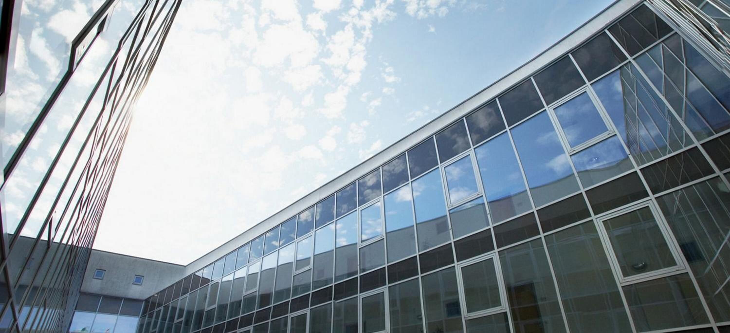 A modern building with a glass facade and a clear sky.