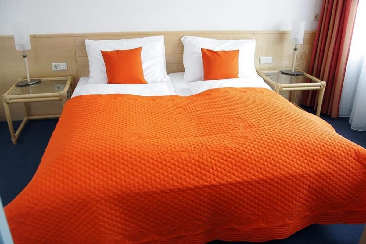 A hotel room with a large bed, two nightstands, and a window with curtains.