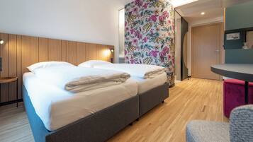 Una habitación de hotel moderna con una cama, una mesita y una silla.