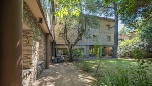 A courtyard with stone walls, a tree, and outdoor seating.