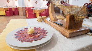 A dining table with a plate of cured meat and a carving stand.