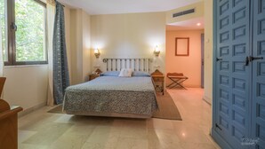 A bedroom with a bed, bedside lamps, a nightstand, a chair, and a door.
