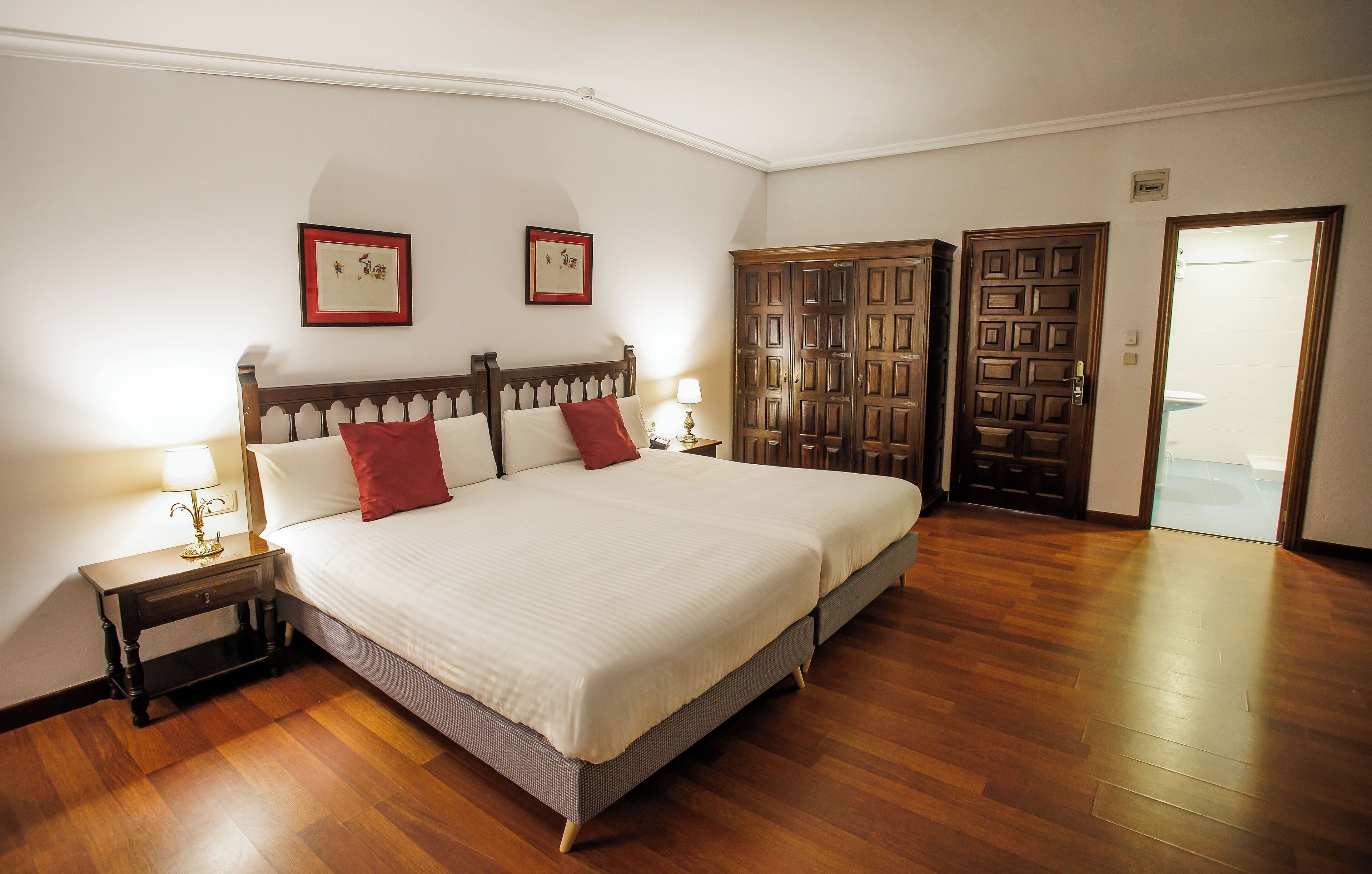 Une chambre bien rangée, avec un grand lit, une armoire en bois et une porte donnant sur une autre pièce.
