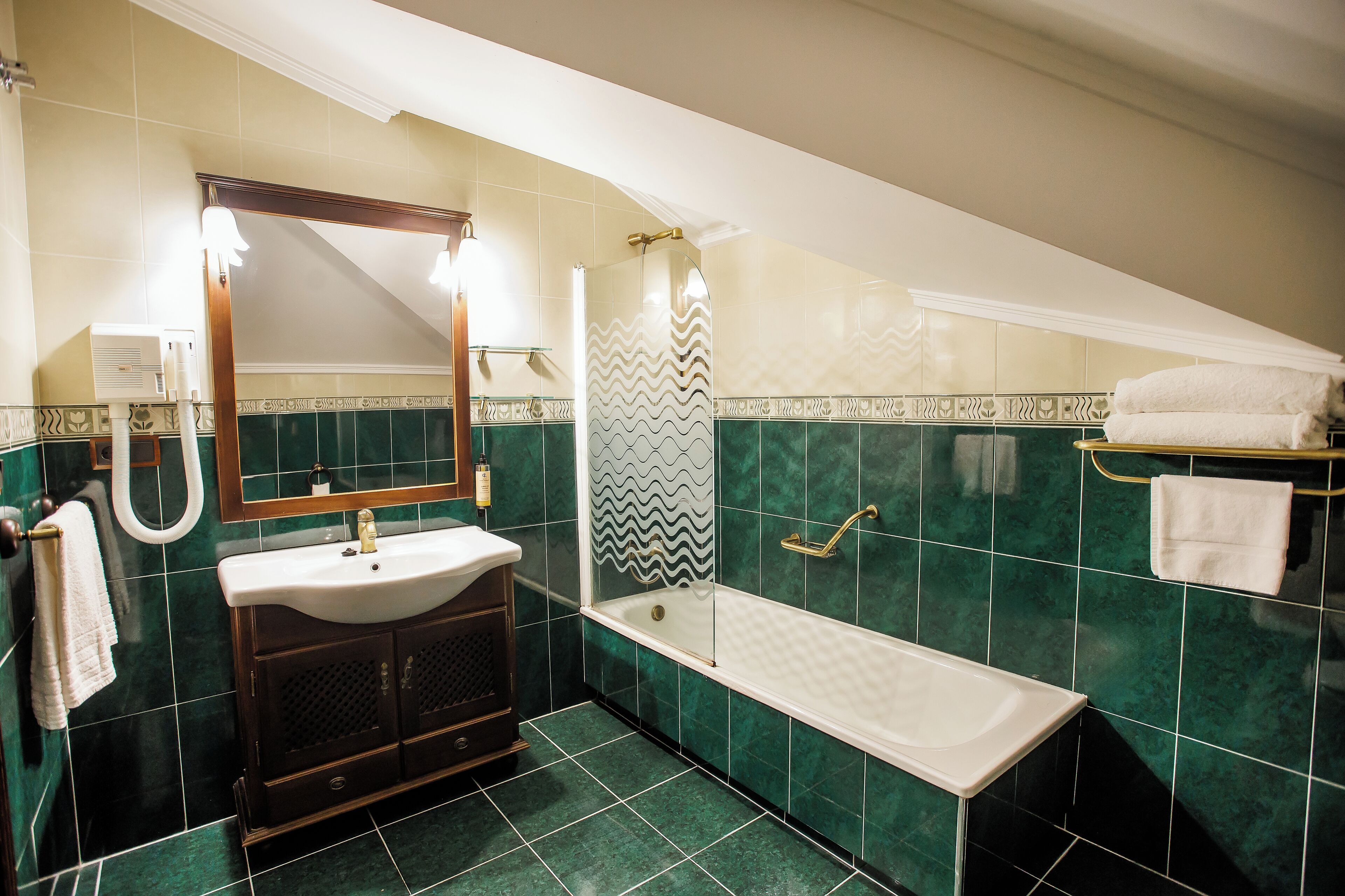 Un baño con bañera, lavamanos, espejo y un perchero para toallas.
