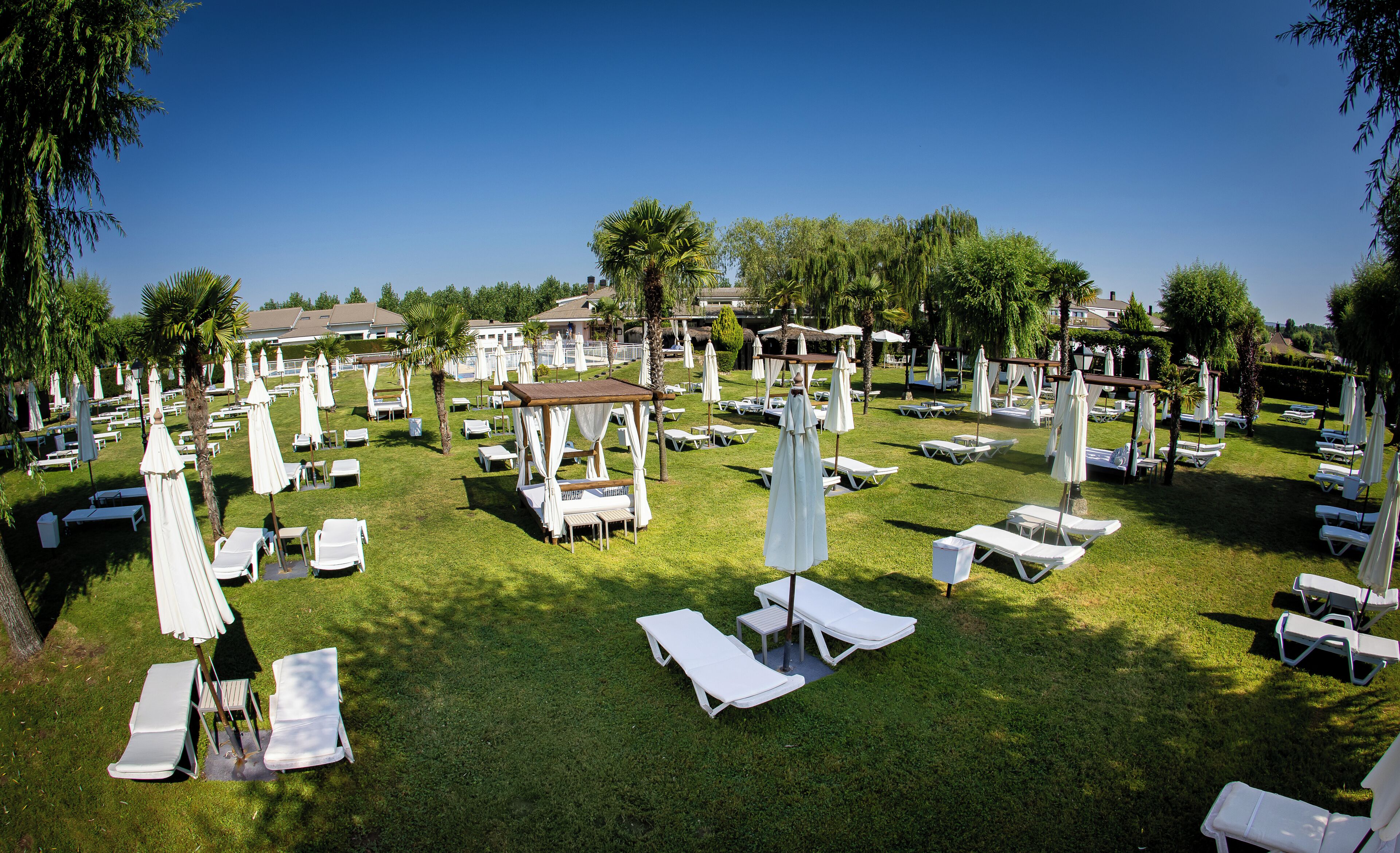 A well-maintained outdoor area with multiple white lounge chairs and umbrellas, arranged in a spacious layout.
