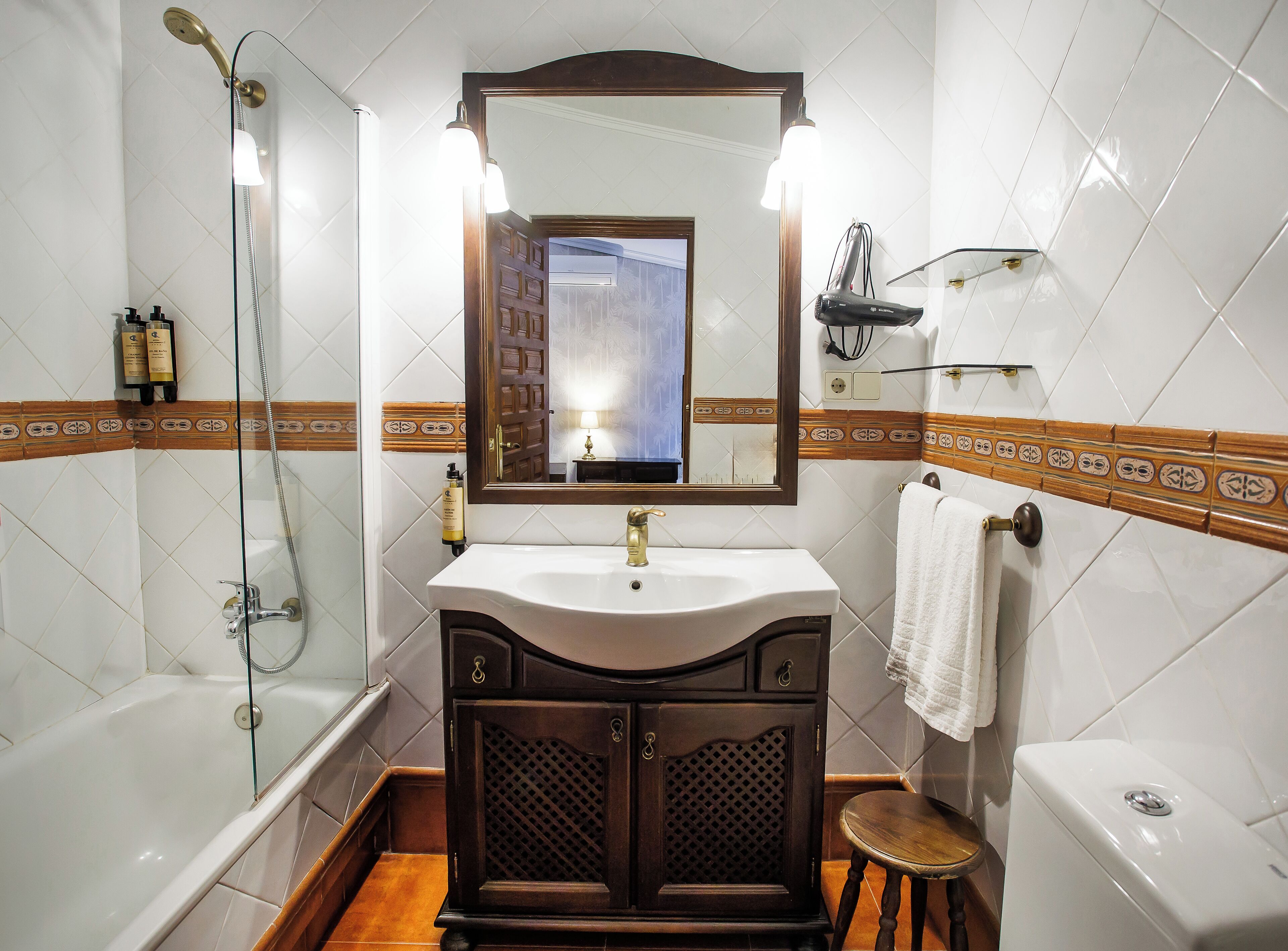 Un baño con bañera, lavabo con espejo y retrete.