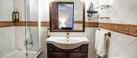 Un baño con bañera, lavabo con espejo y retrete.