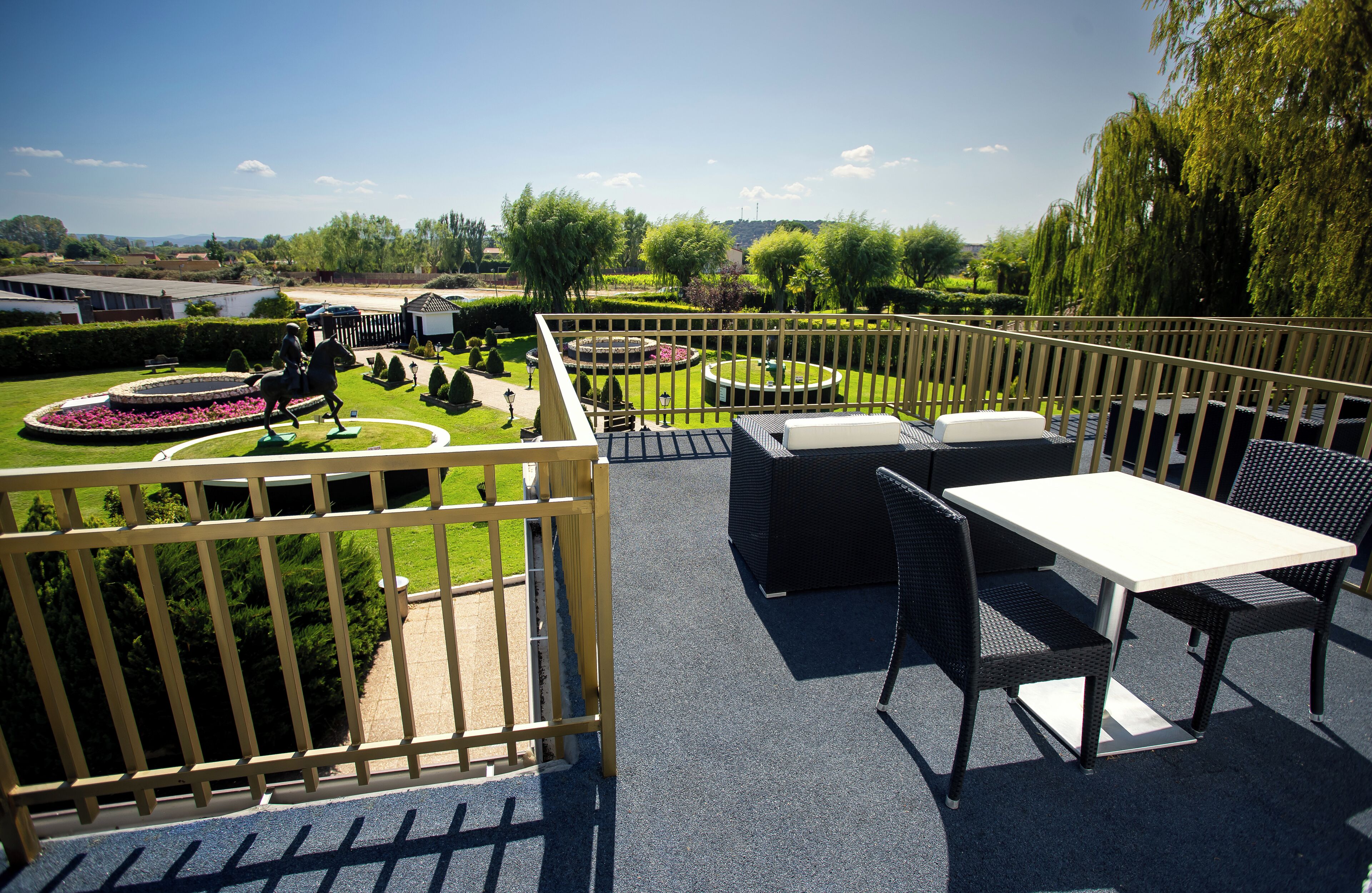 Una terraza en la azotea con mobiliario exterior, vista a un jardín y una valla de madera.