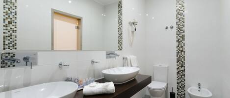 Un baño moderno con un lavamanos grande blanco, un espejo, un inodoro y un bidé.