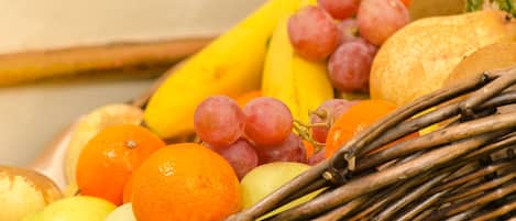 A wicker basket filled with various fruits including bananas, grapes, oranges, and apples.
