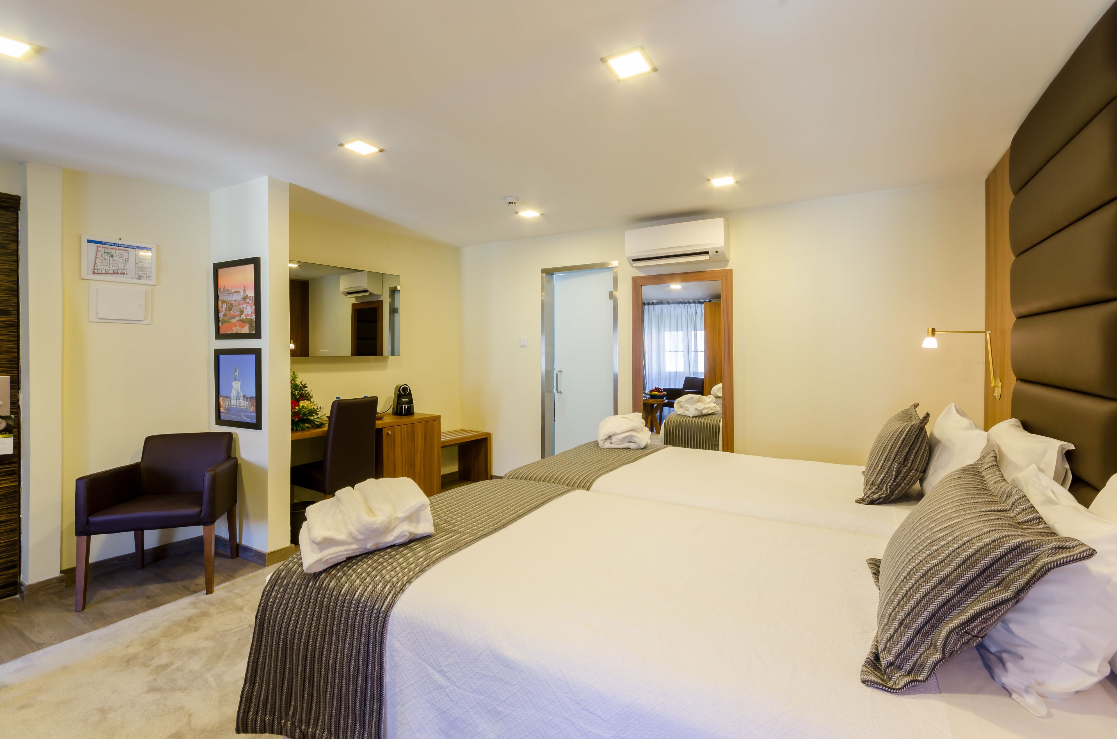 A hotel room with a large bed, a desk, a chair, and a mirror.
