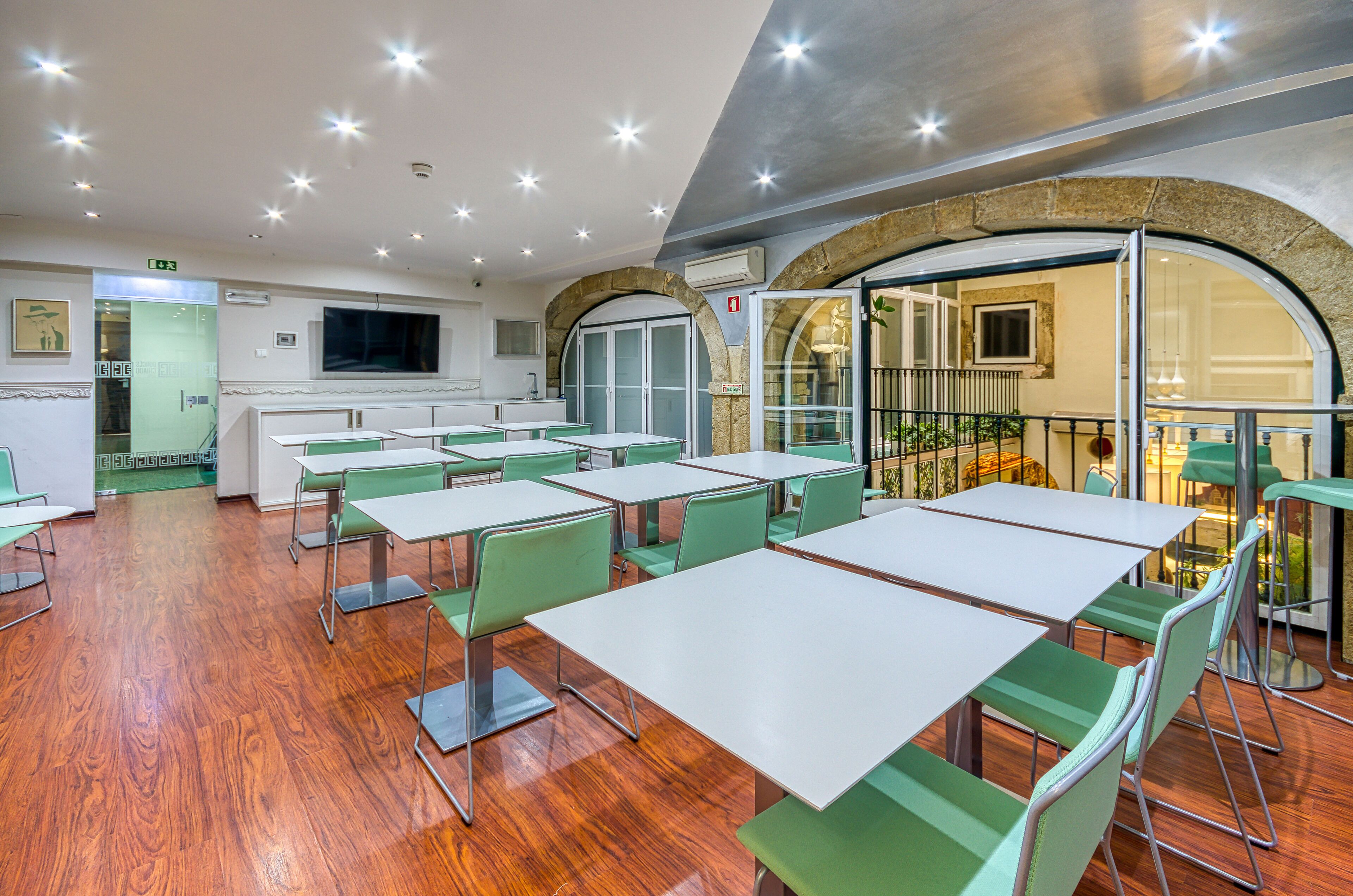 Un comedor con mesas y sillas, una cocina al fondo y una pared de piedra con arco.