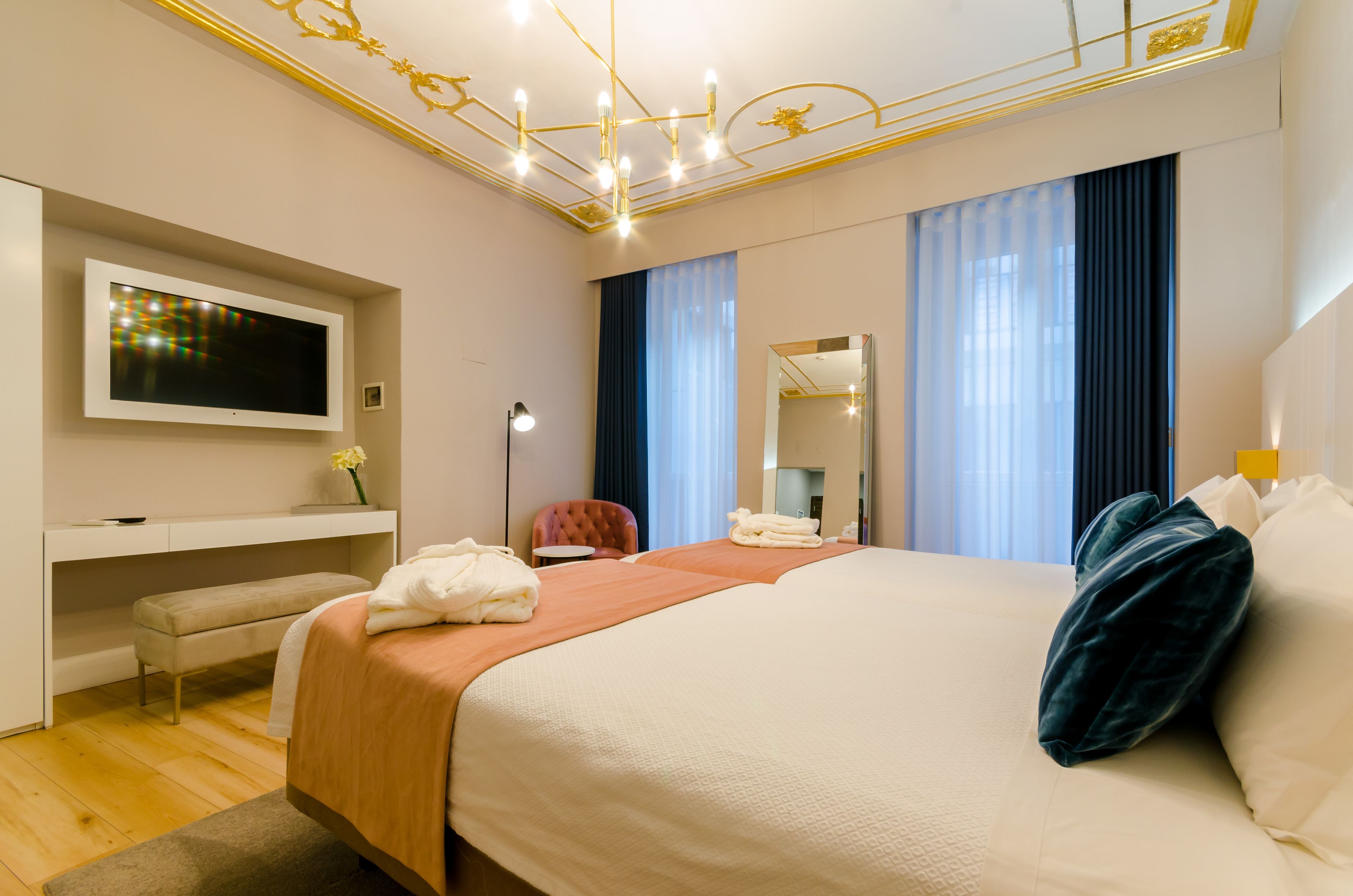 A hotel room with a bed, a desk, a chair, a TV, and a mirror.