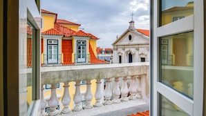 Un balcón con barandilla blanca que da a edificios coloridos con tejas rojas.