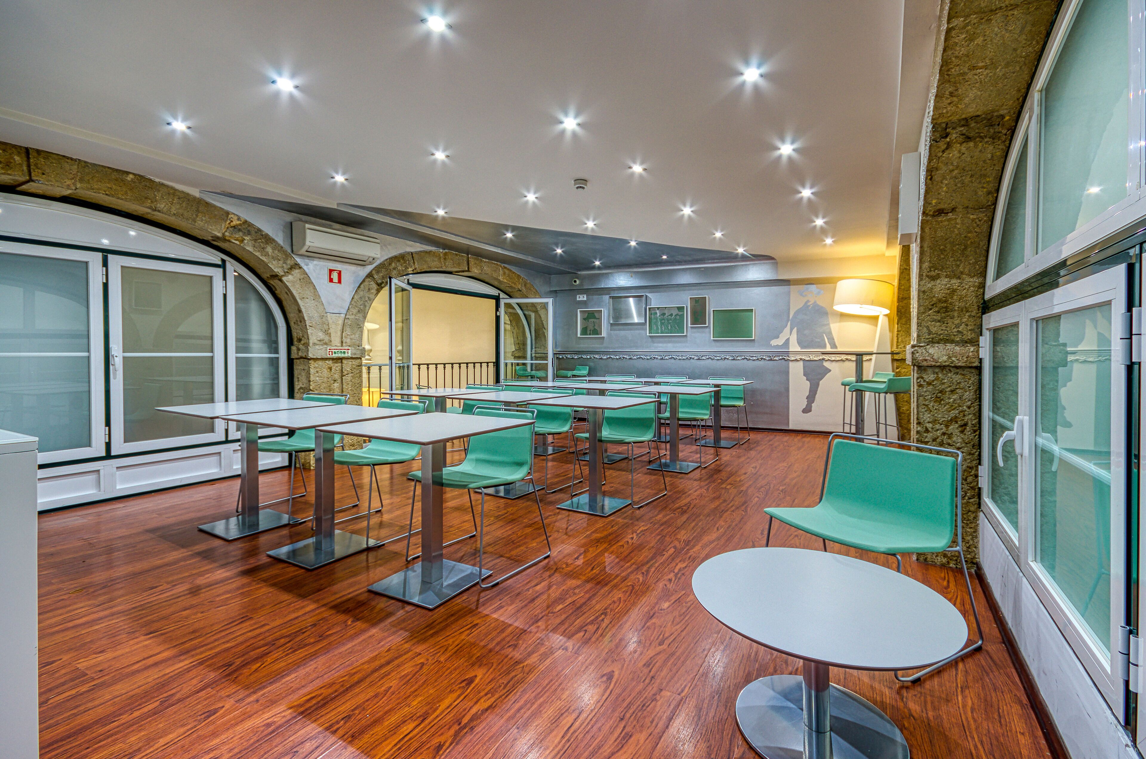Een moderne eethoek met houten vloeren, groene stoelen en witte tafels.