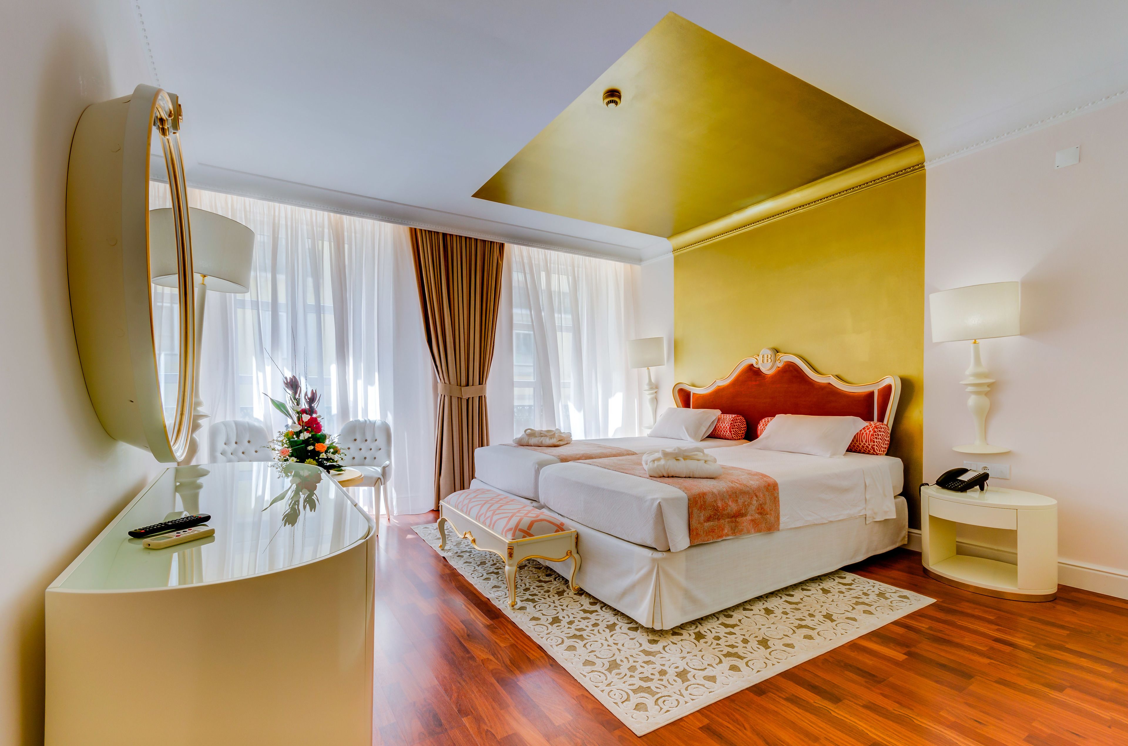Una habitación de hotel con cama, mesita de noche, lámpara y un espejo grande.