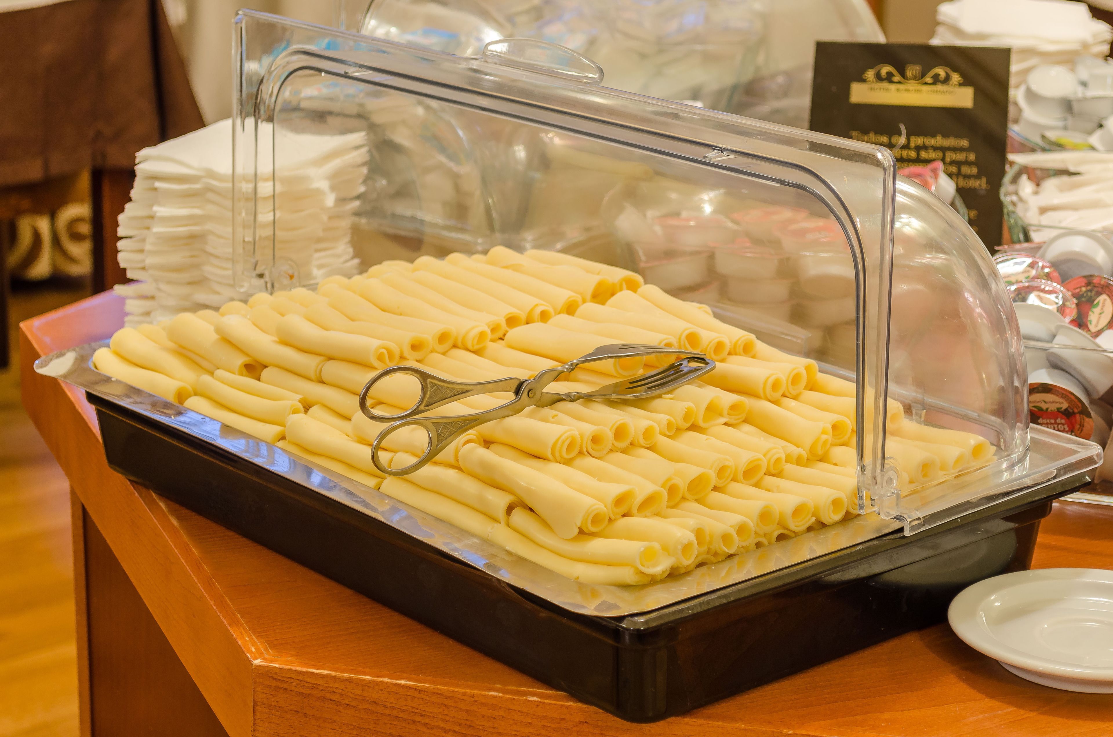 Un buffet recouvert d’une cloche en verre transparent, contenant des rouleaux de pâtes joliment disposés et une paire de ciseaux sur le plateau.