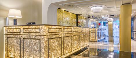 A reception area with a marble counter, a chandelier, and a modern design.