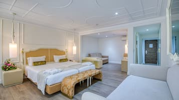 Une chambre d’hôtel moderne, dotée d’un grand lit, d’un canapé, d’un bureau et d’une salle de bain visible à travers une porte en verre.
