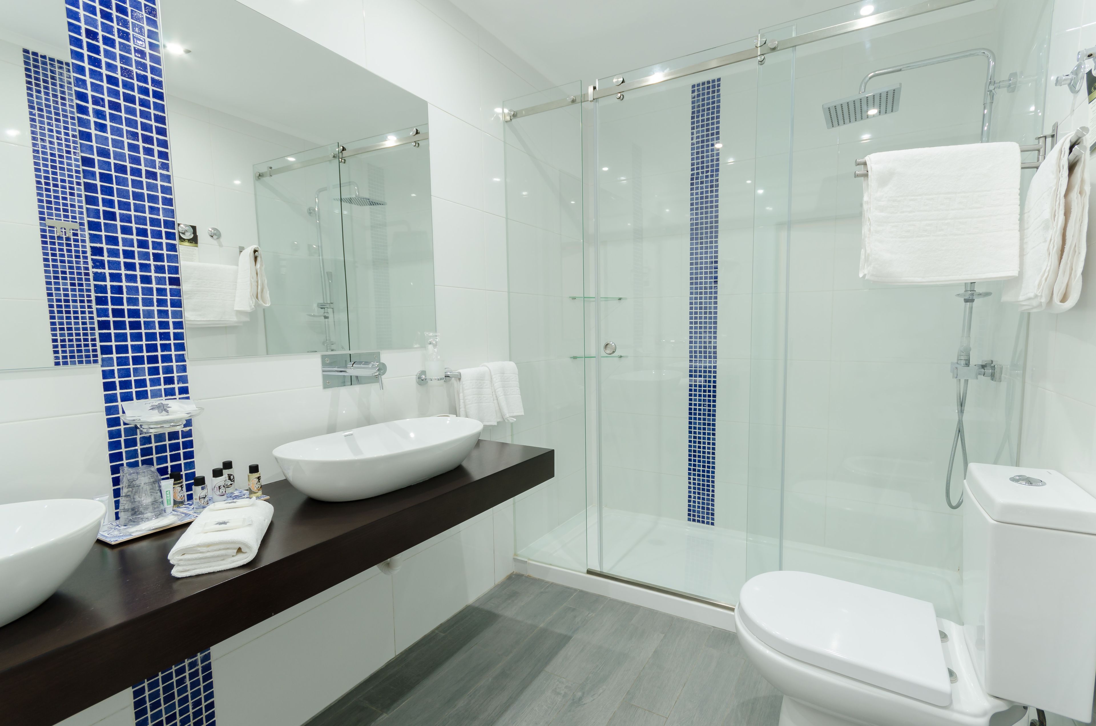 Un baño moderno con ducha de vidrio, un lavabo blanco y un inodoro.