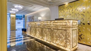 A reception area with a marble counter, a chandelier, and a patterned wall.