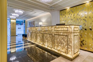 A reception area with a marble counter, a chandelier, and a patterned wall.