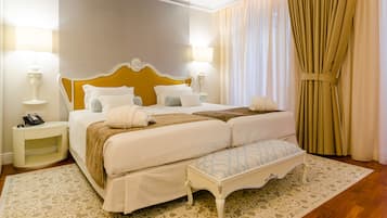 Habitación de hotel ordenada con una cama grande, lámparas de noche, teléfono en la mesita y una alfombra estampada.