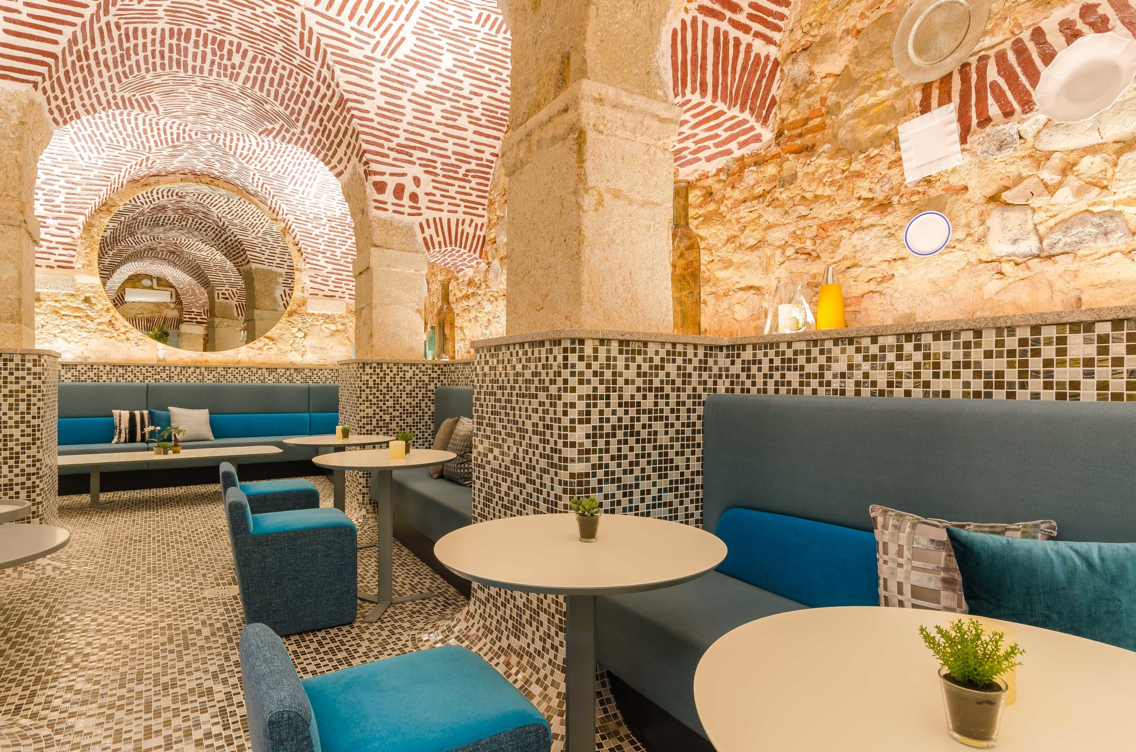 A modern interior with a patterned ceiling, seating areas, and a tiled floor.