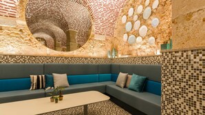 Un interior moderno con una pared curva, un espejo circular y un sofá azul.