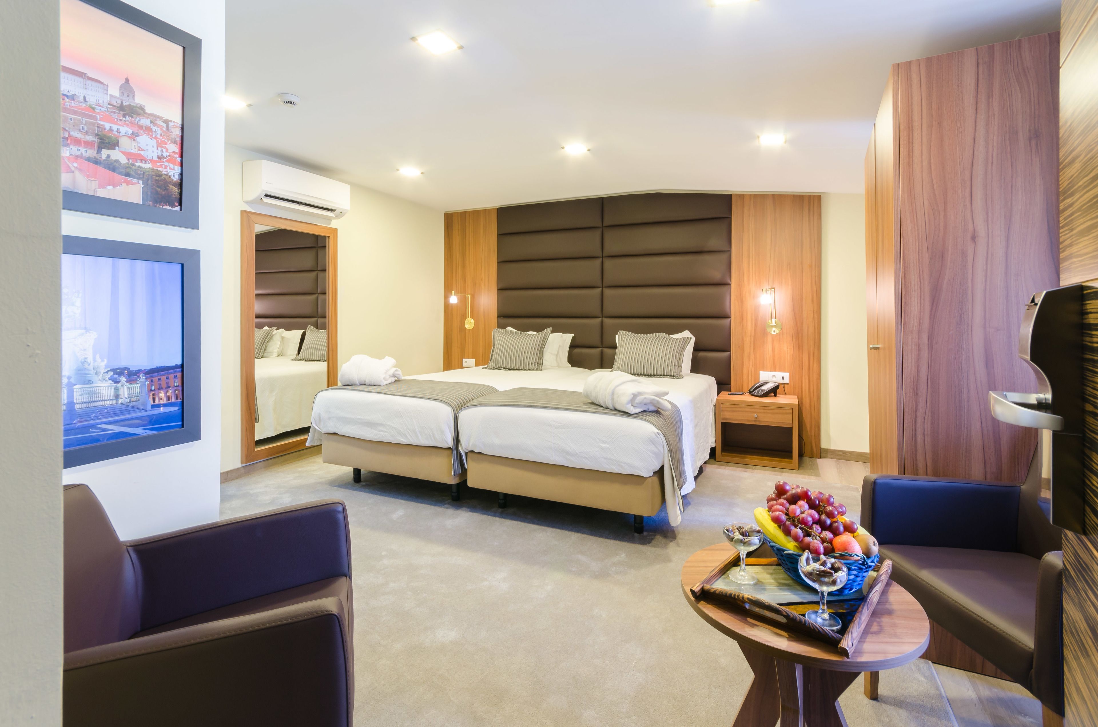 Una habitación de hotel moderna con una cama grande, dos mesitas de noche, un escritorio con una silla y una cesta de frutas.