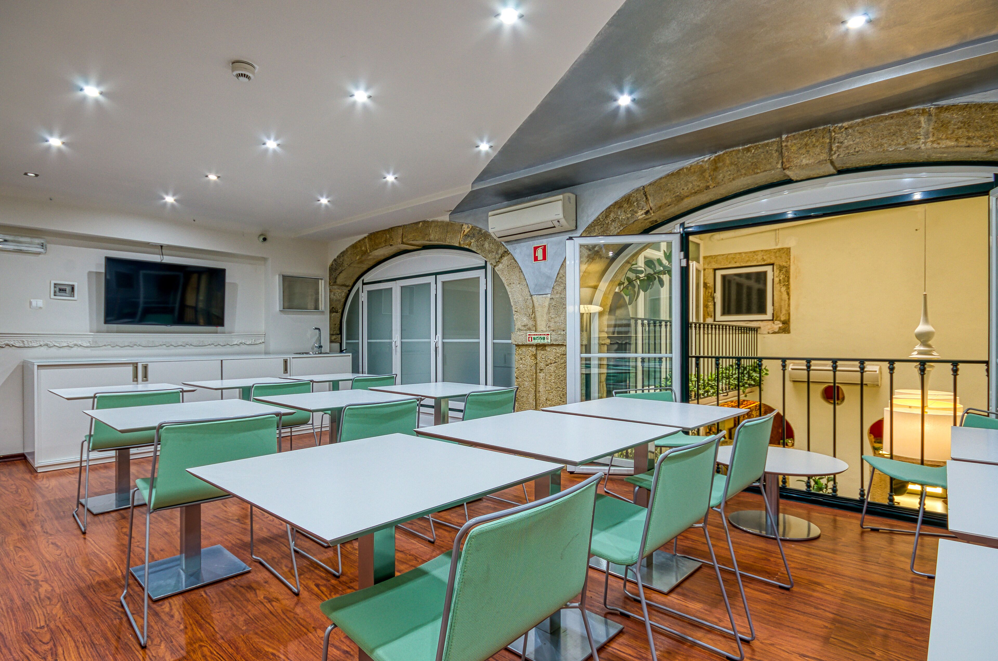 A dining area with tables and chairs, a stone archway, and a view of the outdoors.