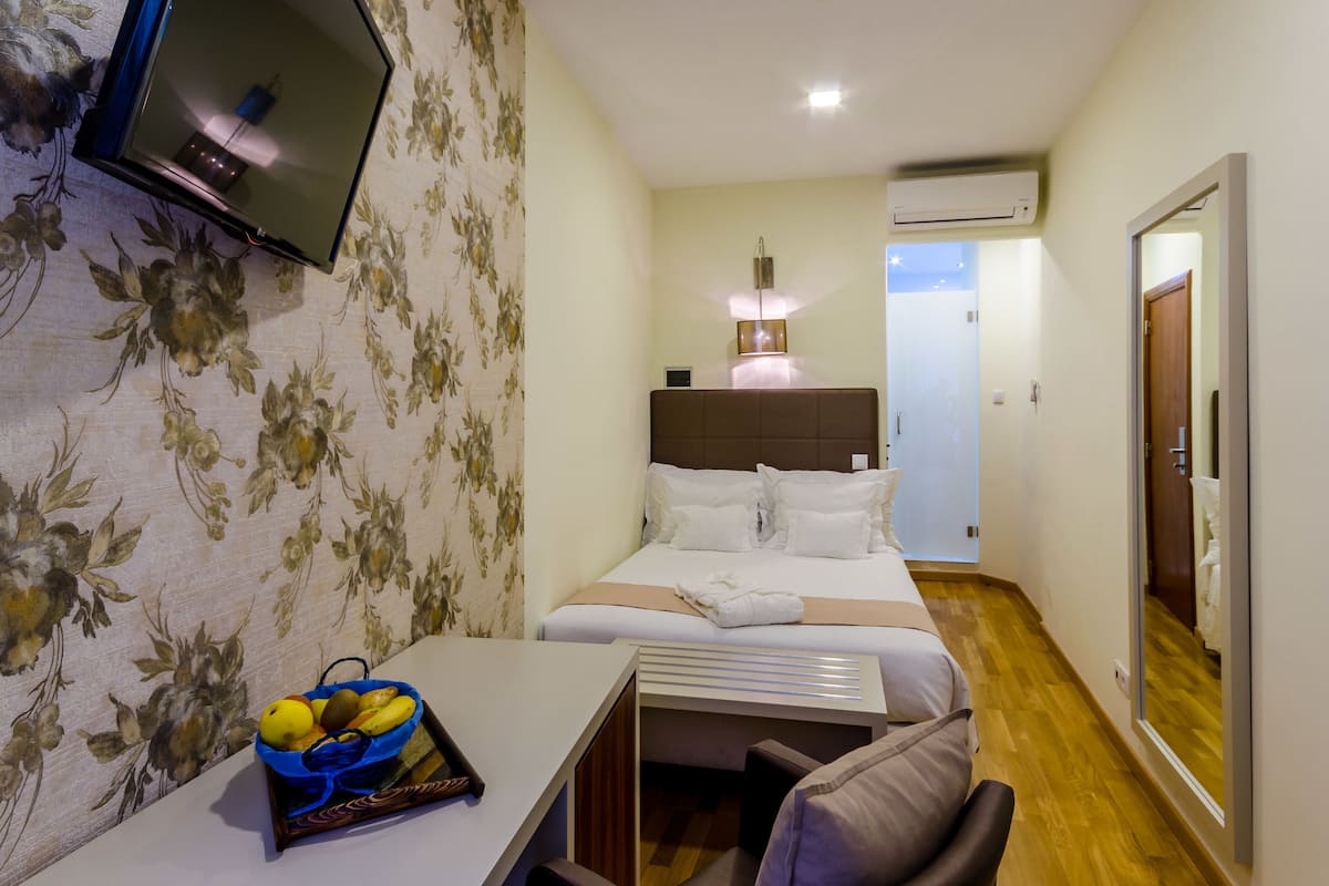 Ein Hotelzimmer mit Bett, Schreibtisch mit Obstkorb, Fernseher und angrenzendem Badezimmer.