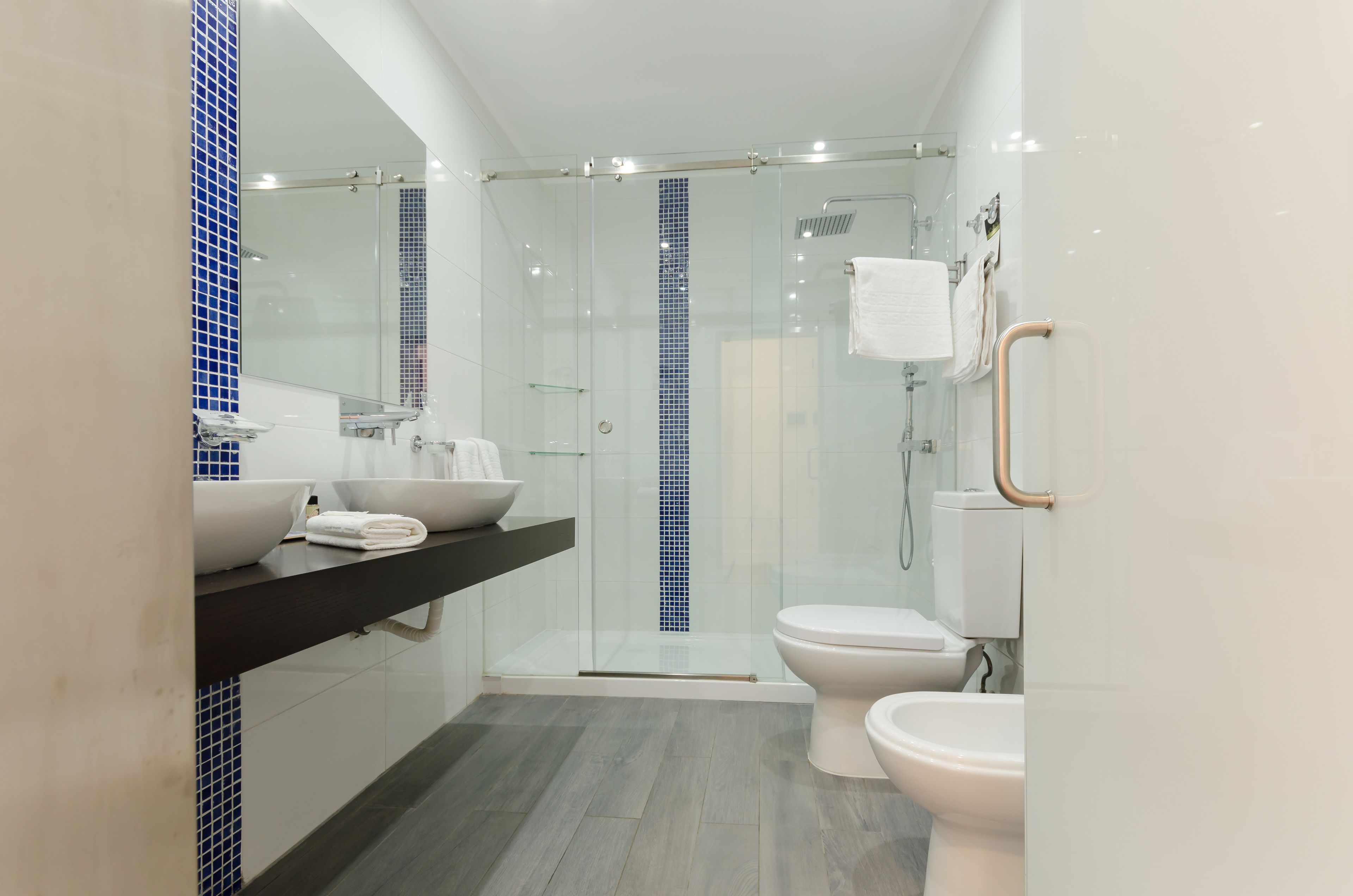 A modern bathroom with a glass-enclosed shower, a white toilet, and a vanity with a bowl sink.
