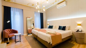 Una habitación de hotel con una cama grande, una mesita pequeña, una silla, una lámpara de noche y una mesita de noche con un teléfono.