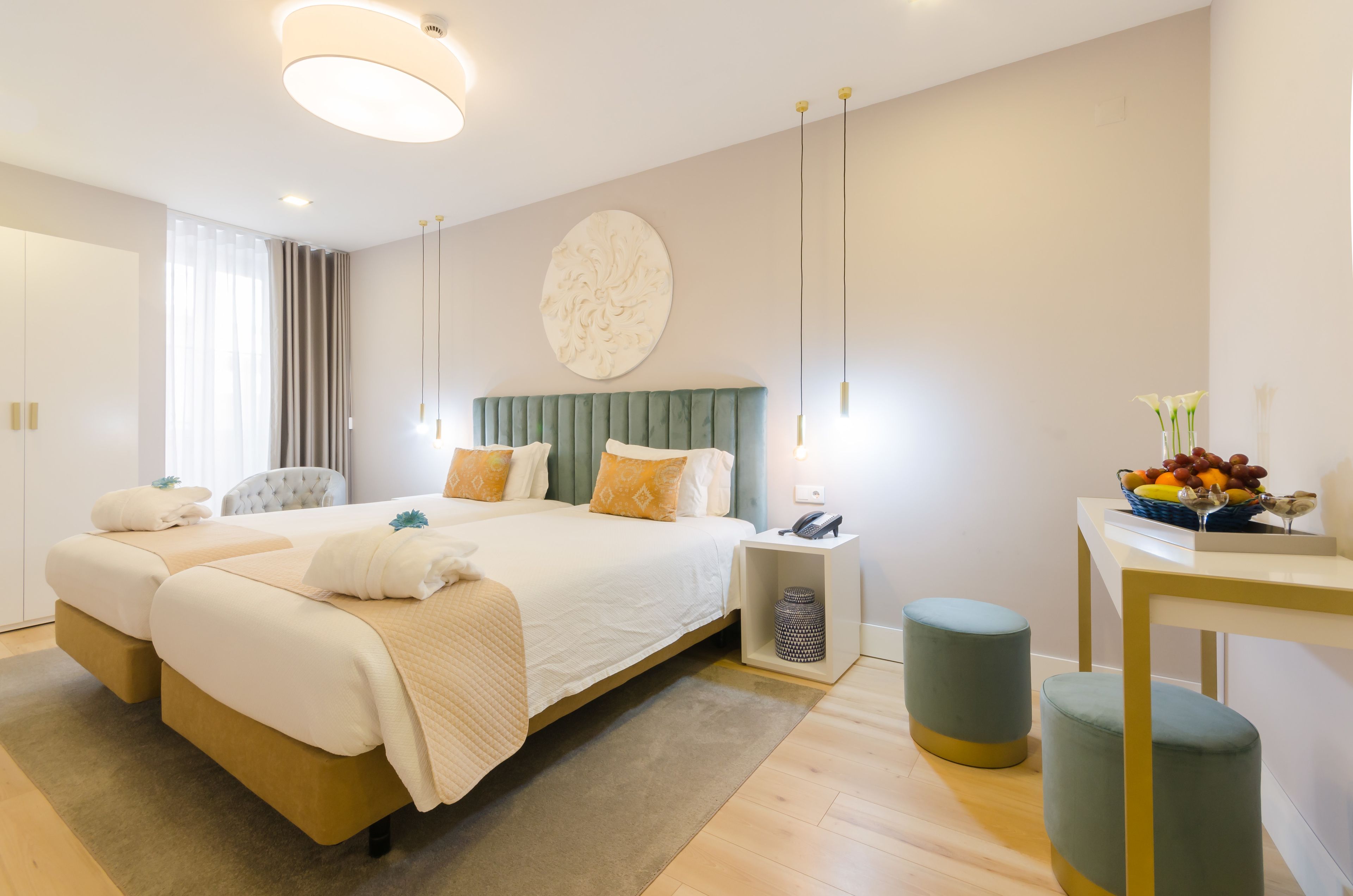 A modern hotel room with a large bed, bedside tables, a desk, and a fruit bowl.