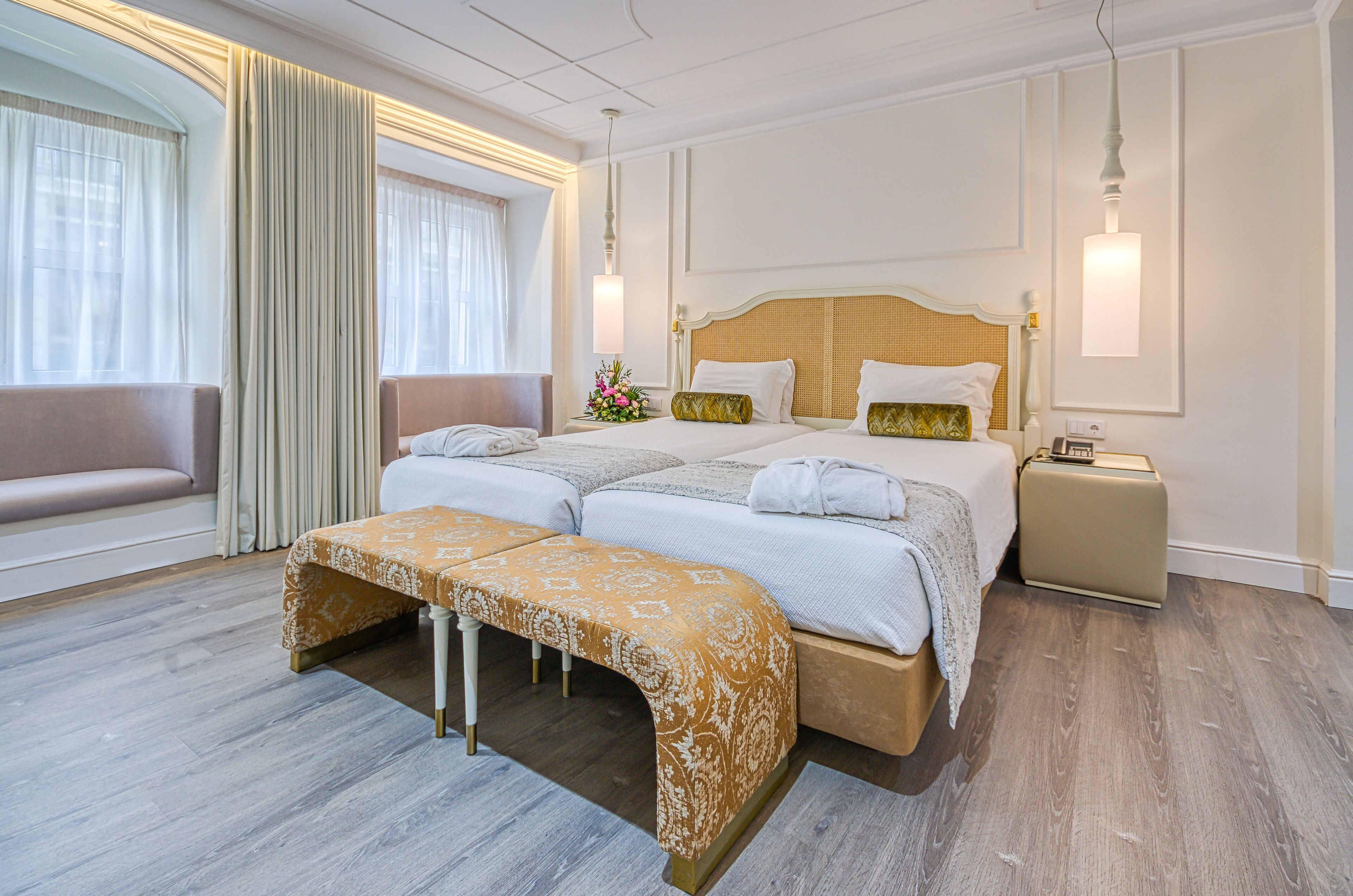 A hotel room with a large bed, a bench, a bedside table, and a nightstand.