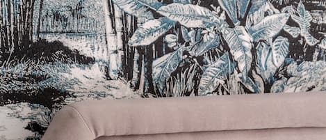 Een bed met een deken waarop een tropisch tafereel is afgebeeld.