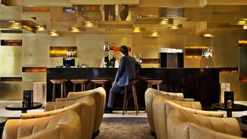 A bar area with leather seating, a counter, and a bartender.
