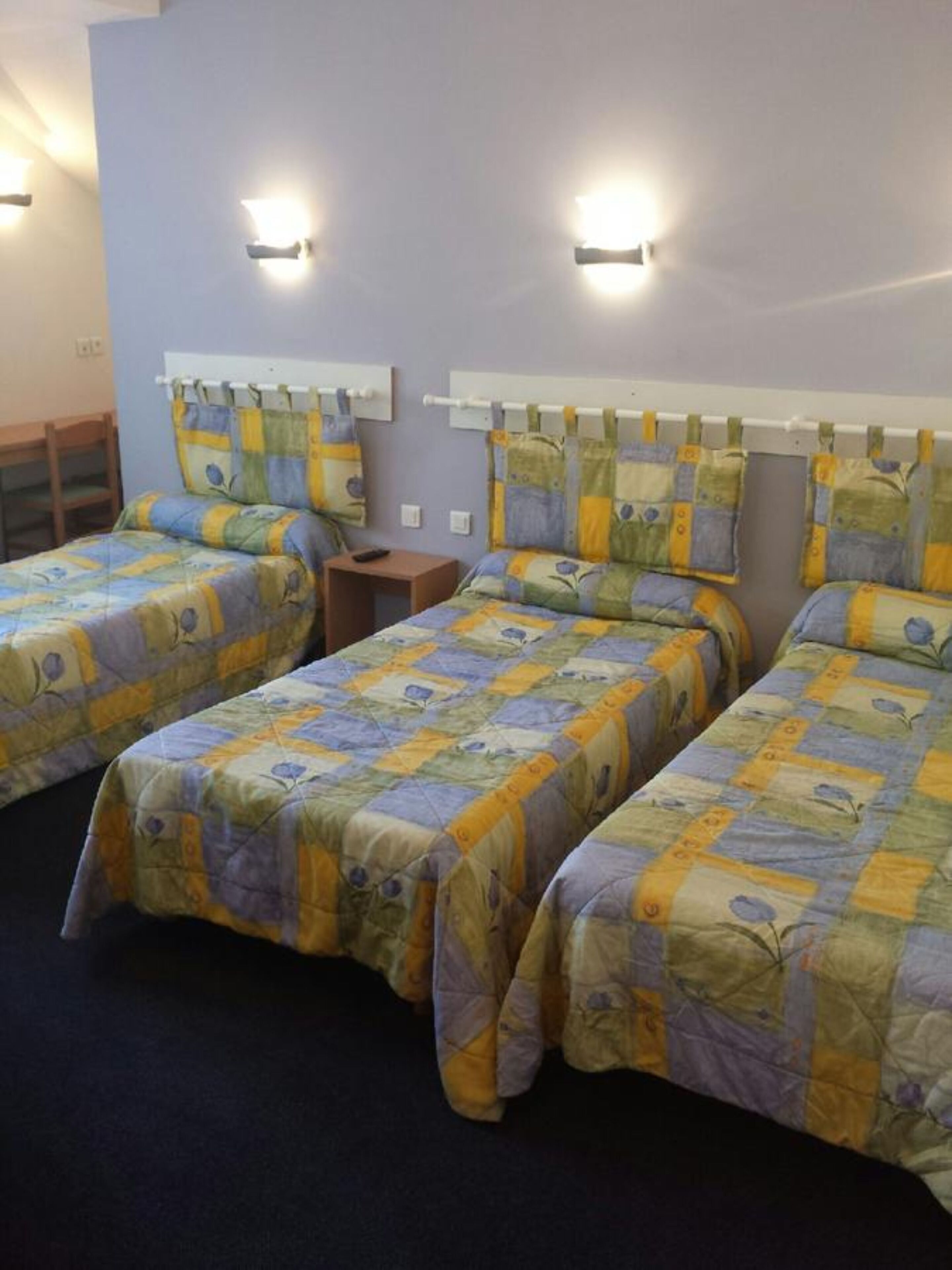 Een hotelkamer met twee enkele bedden, een tafeltje en twee wandlampen.