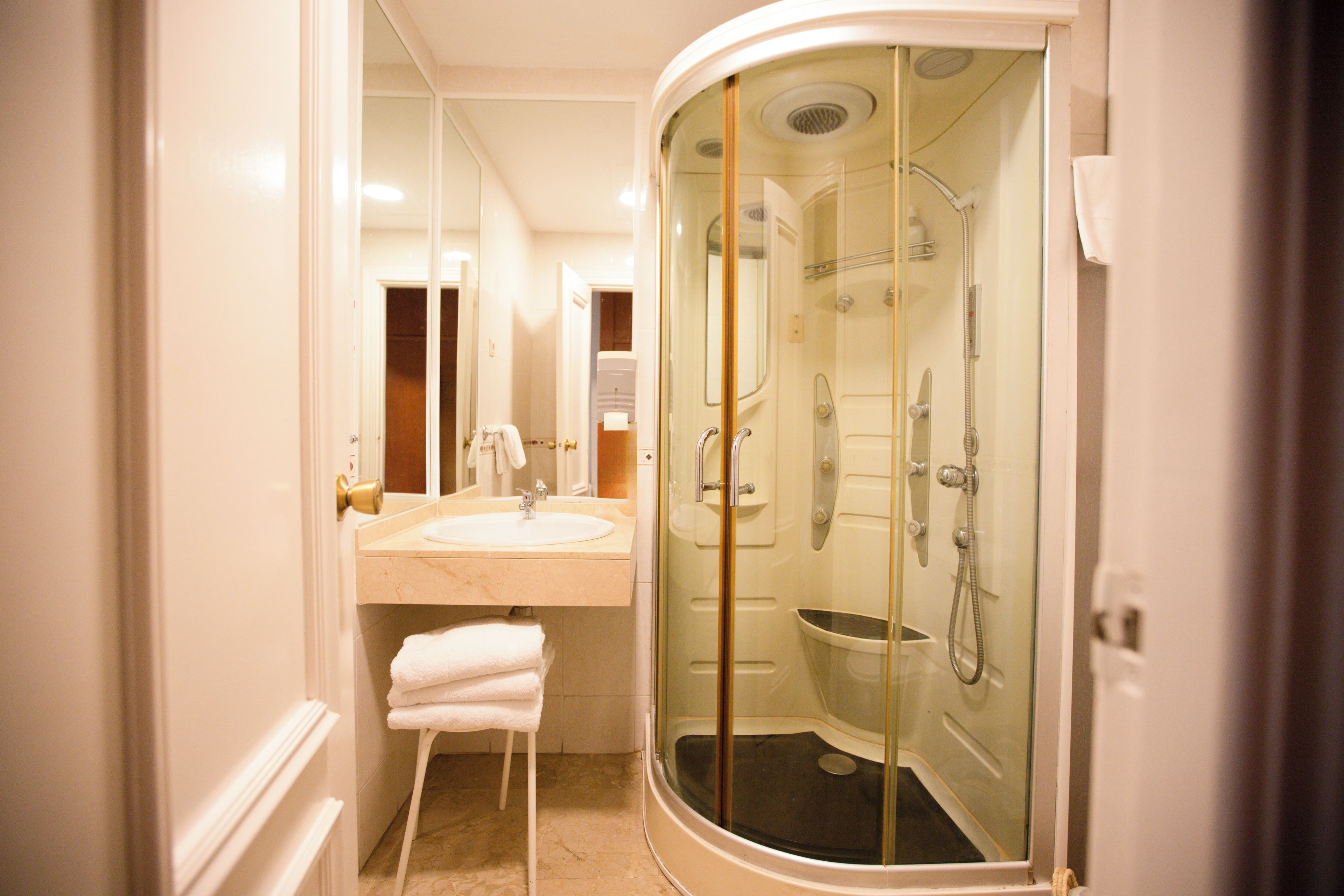 A modern bathroom with a glass-enclosed shower, a sink with a mirror, and a towel rack.