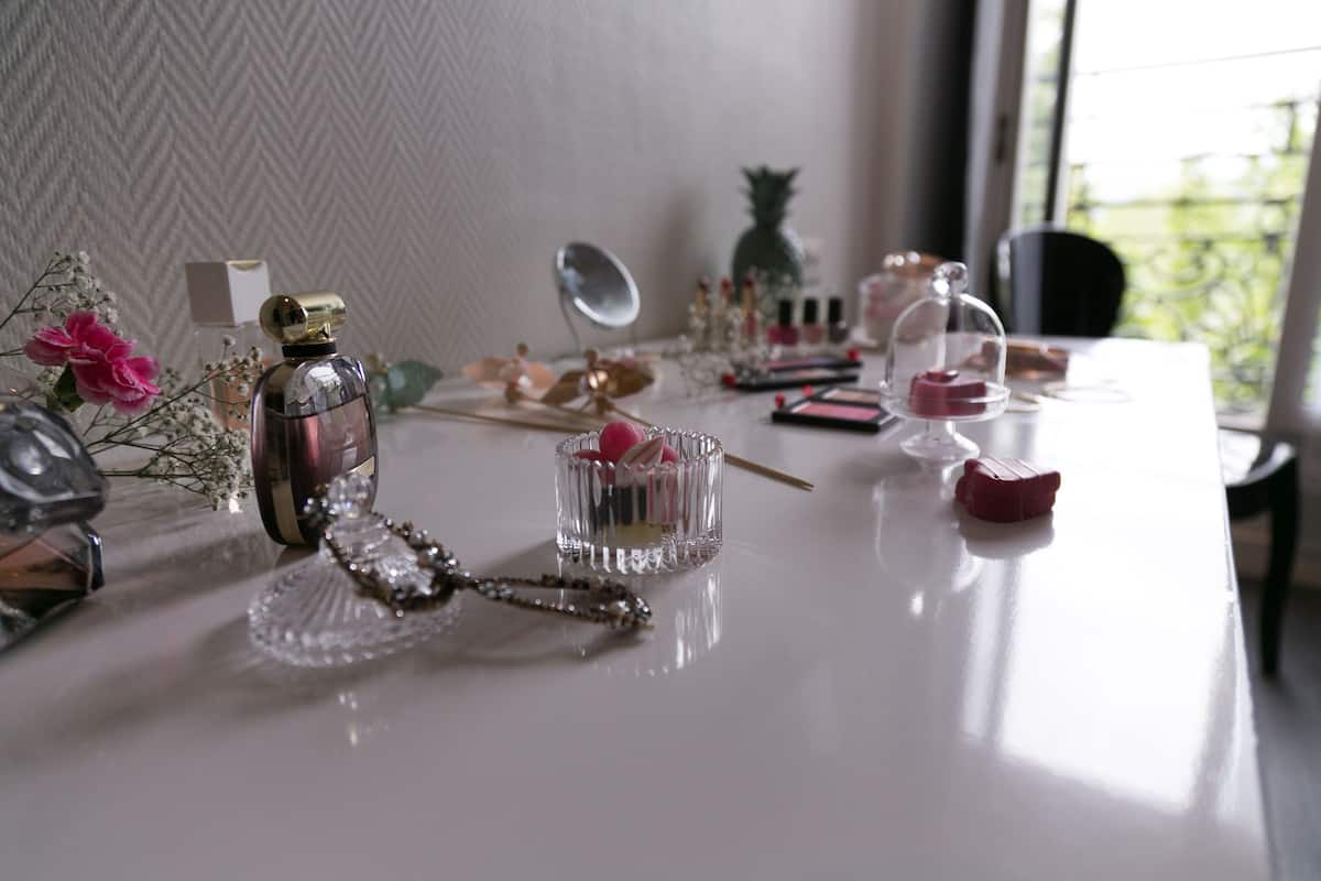 Une table sur laquelle sont disposés divers produits de soins personnels, un miroir décoratif et un petit ananas.